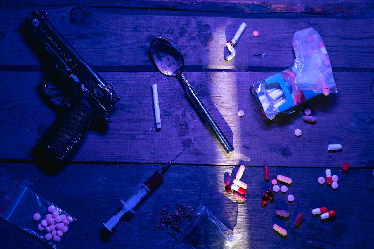 Crafting Captivating Headlines: Your awesome post title goes here Intriguing still life image depicting pills, a gun, and syringe under dramatic lighting.